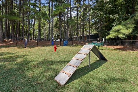 A playground with a slide in the middle of a grassy area.