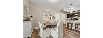 A dining room with a table set for two and a kitchen in the background.