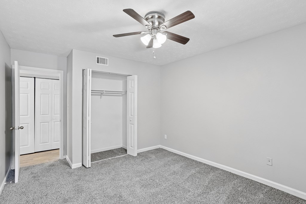 A room with a ceiling fan and a carpeted floor.