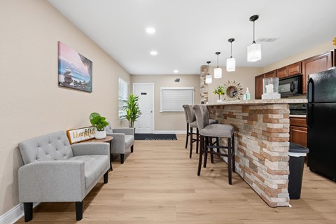 A kitchen with a bar area and a grey couch.