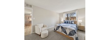 A bedroom with a bed, chair, and window.