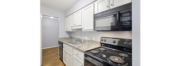A kitchen with black appliances and white cabinets.