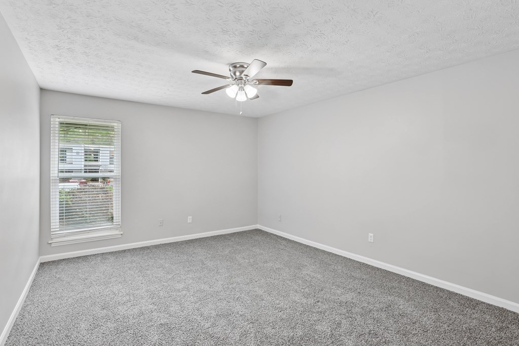 A room with a ceiling fan and carpeted floor.