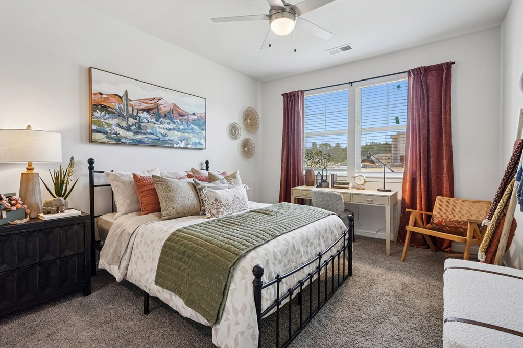 A bedroom with a large bed, a desk, and a painting on the wall.
