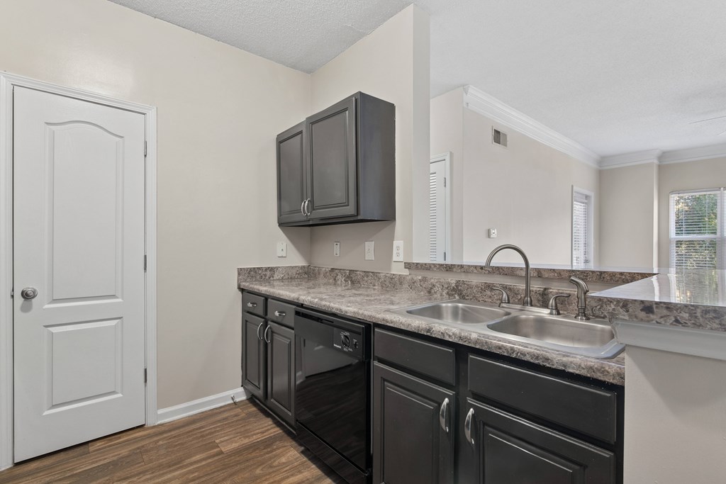 A kitchen with black cabinets and a white door.