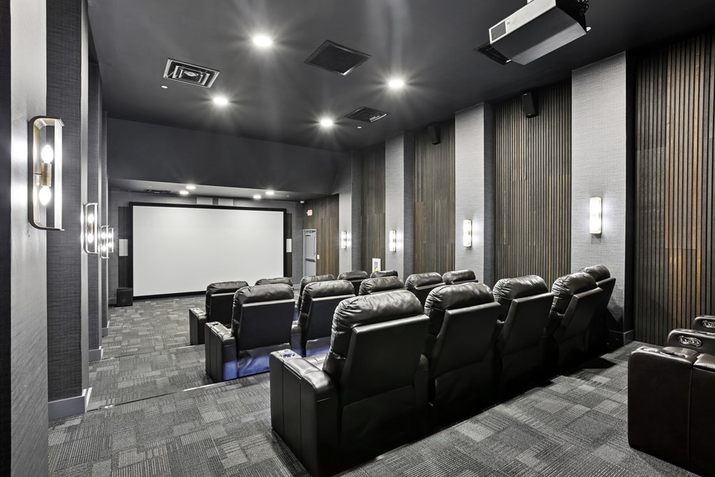 A row of black leather seats in a movie theater.