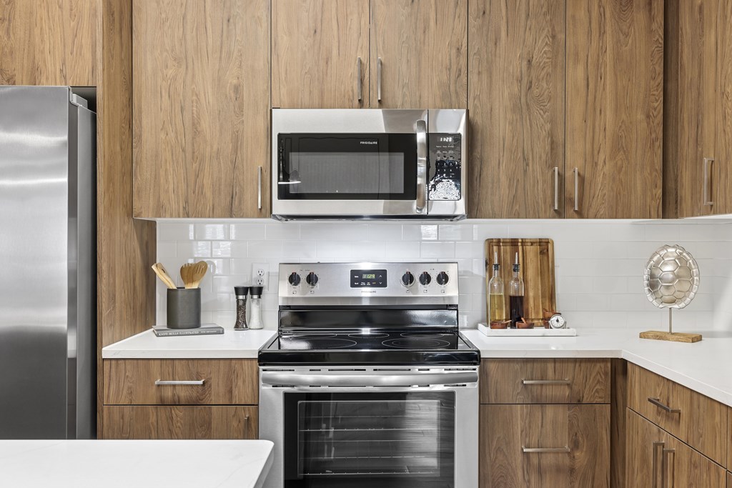 A modern kitchen with a stainless steel refrigerator, a microwave, and a stove top oven.at The Exchange at Crestview Apartments, Crestview, FL, 32536