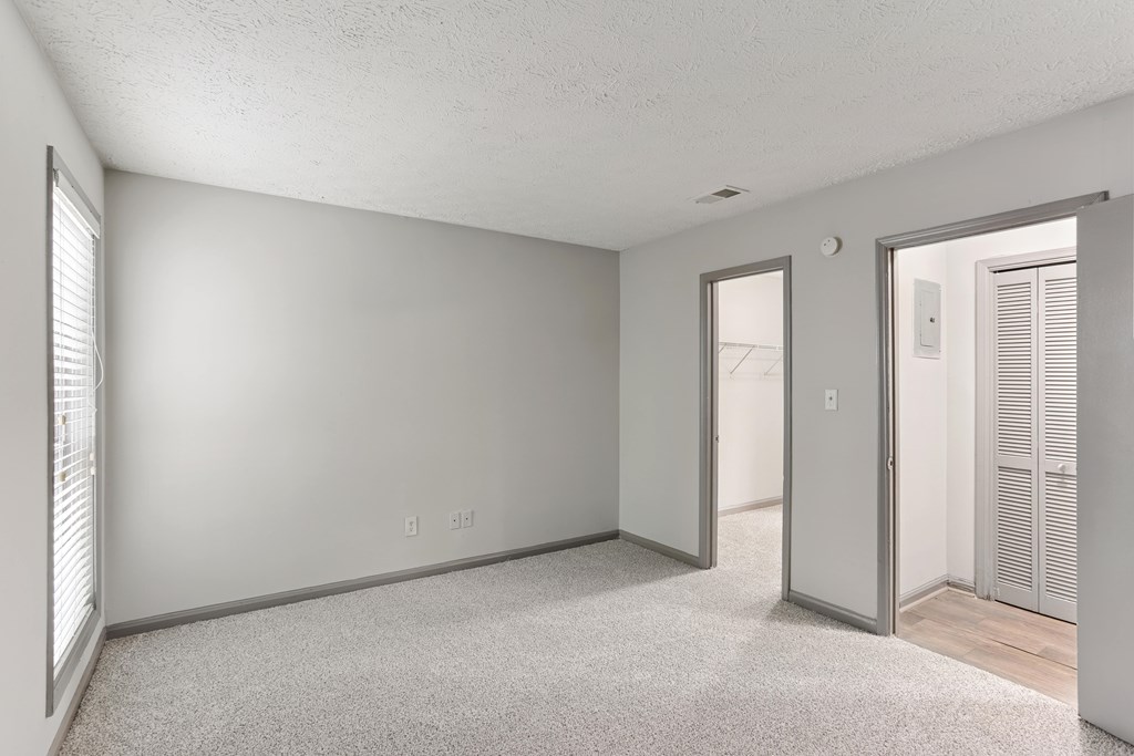 A room with a carpeted floor and a door leading to another room.