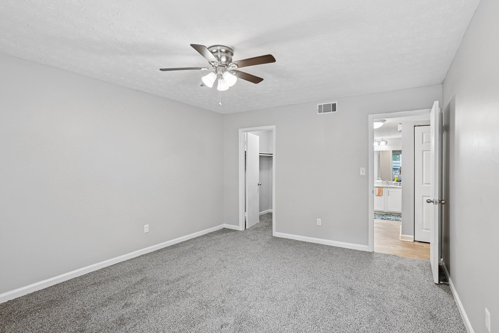 A room with a ceiling fan and carpeted floor.
