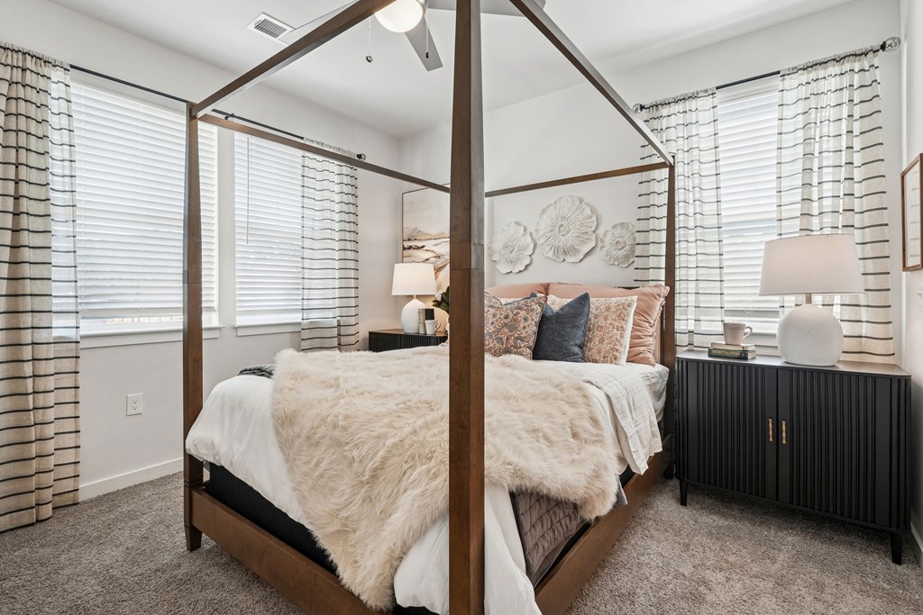 A bedroom with a four poster bed and a lamp on a side table.