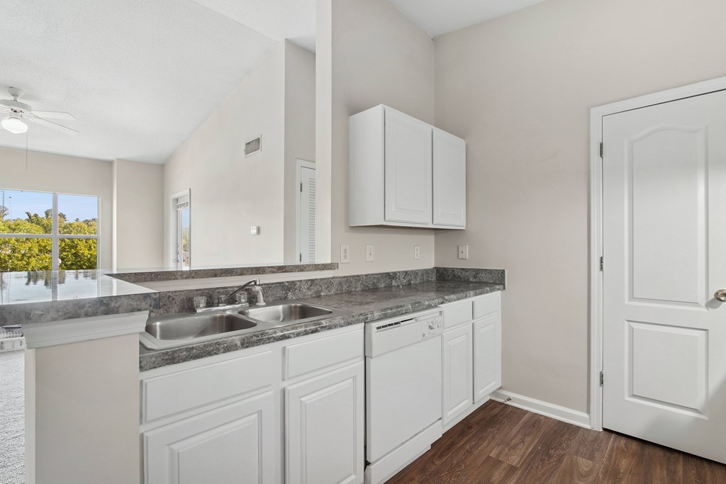 A kitchen with white cabinets and a marble countertop.