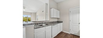 A kitchen with white cabinets and a marble countertop.