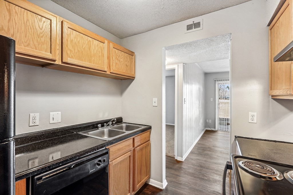 an empty kitchen with wood cabinets and a black stove and sink
