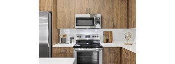 A modern kitchen with a stainless steel refrigerator, a microwave, and a stove top oven.