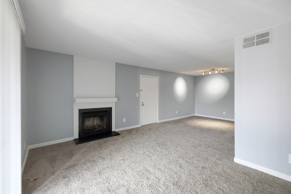 an empty living room with a fireplace and white carpet  at Governors House, Alabama, 35805