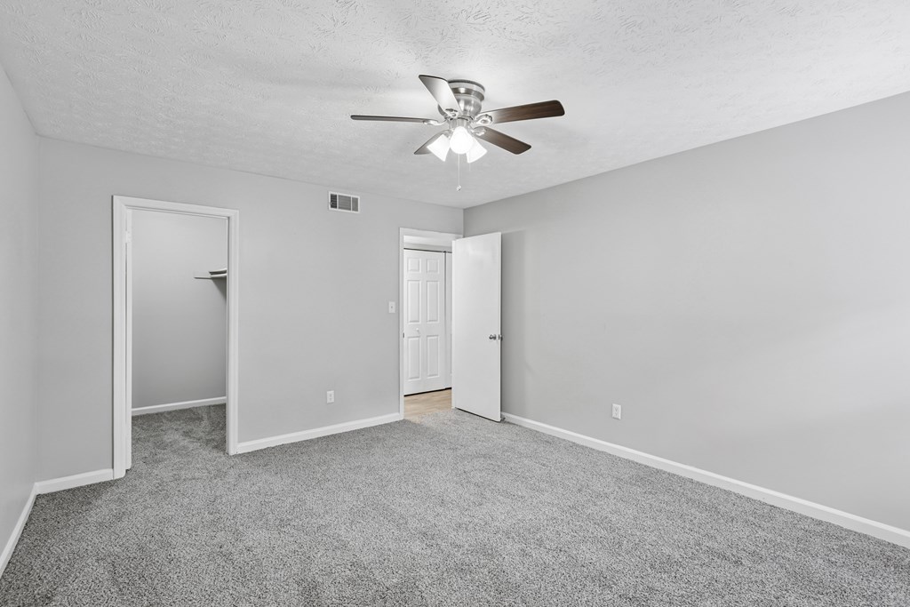 A room with a ceiling fan and carpeted floor.