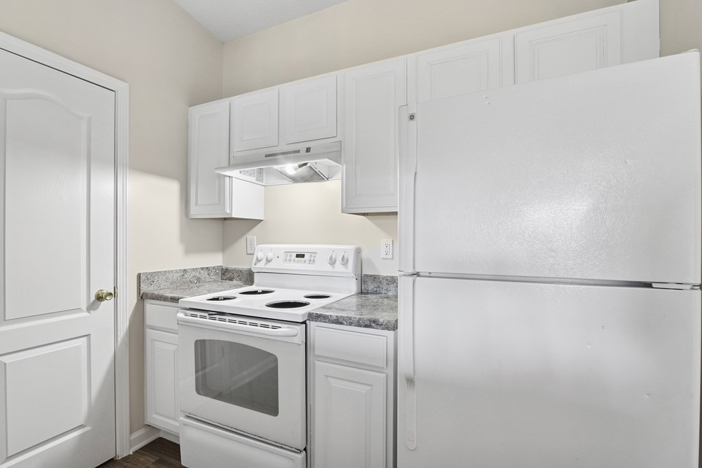 A white kitchen with a stove and refrigerator.