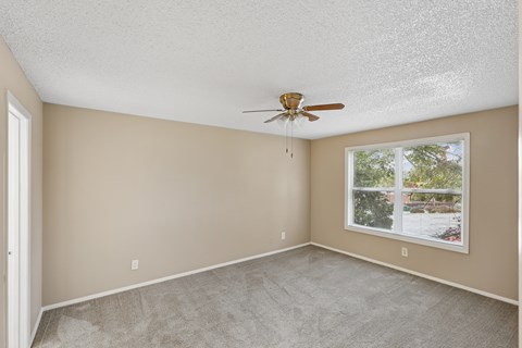 A room with a ceiling fan and a window showing an outdoor view.