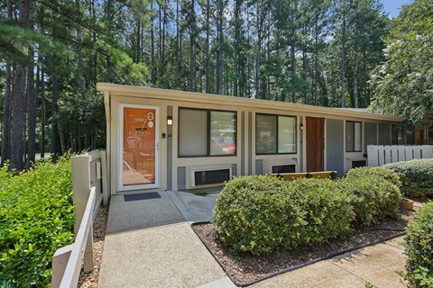 A modern house with a wooden exterior and glass windows is surrounded by a well-manicured garden.