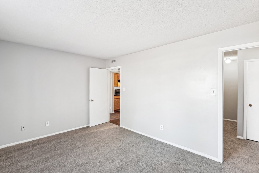 an empty living room with white walls and carpeting
