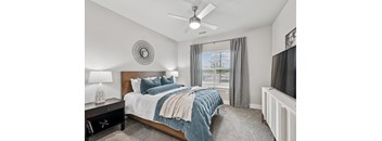A bedroom with a bed, nightstand, and window.
