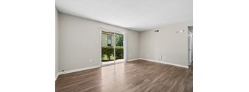 A room with wooden flooring and a sliding glass door leading to a garden.