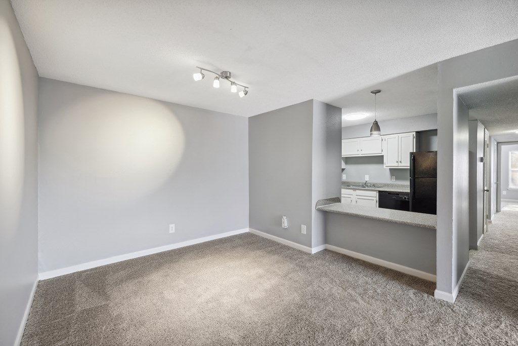 the living room and kitchen of an apartment with gray walls and carpet  at Governors House, Huntsville