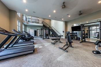a gym with treadmills and other exercise equipment and a staircase at The Monroe Apartments, Austin, TX, 78741