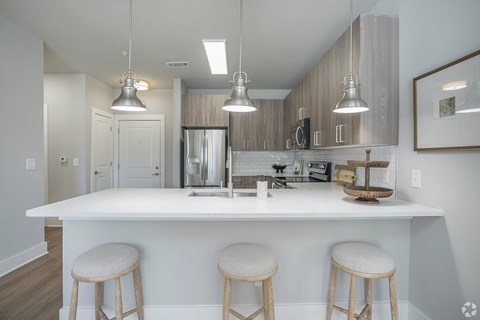 A kitchen with a white island and bar stools.