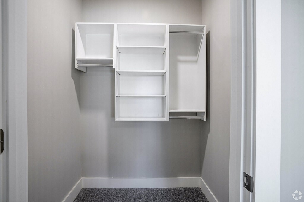 A white shelving unit with several compartments is mounted on a wall at The Delaney at East Park Apartments, Kennesaw, GA