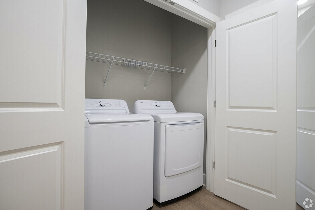 Two white washing machines in a small laundry room at The Delaney at East Park Apartments, Kennesaw, GA, 30144