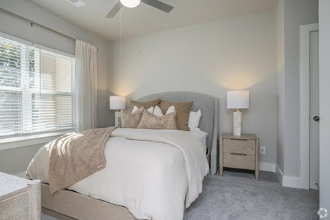 A bedroom with a bed, nightstand, and window.