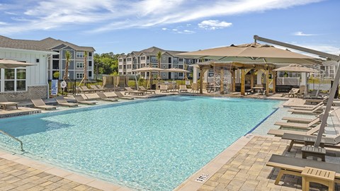 A large swimming pool with a sun lounger area and a building in the background at The Exchange at Crestview Apartments, Crestview, FL