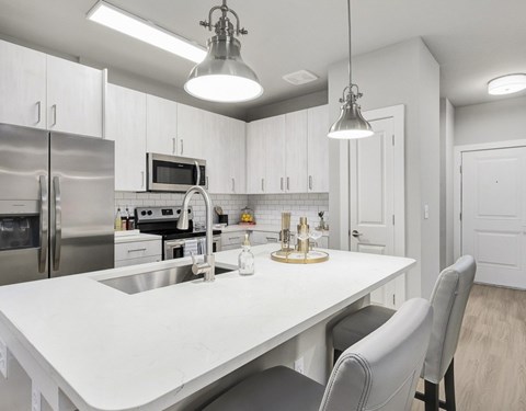 A modern kitchen with a white table and grey chairs at The Exchange at Crestview Apartments, Crestview, 32536