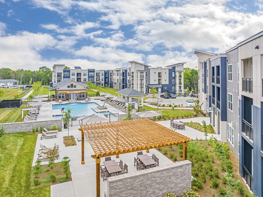 A large outdoor swimming pool surrounded by a wooden deck and lounge chairs at The Percy Apartments, Tennessee, 37214
