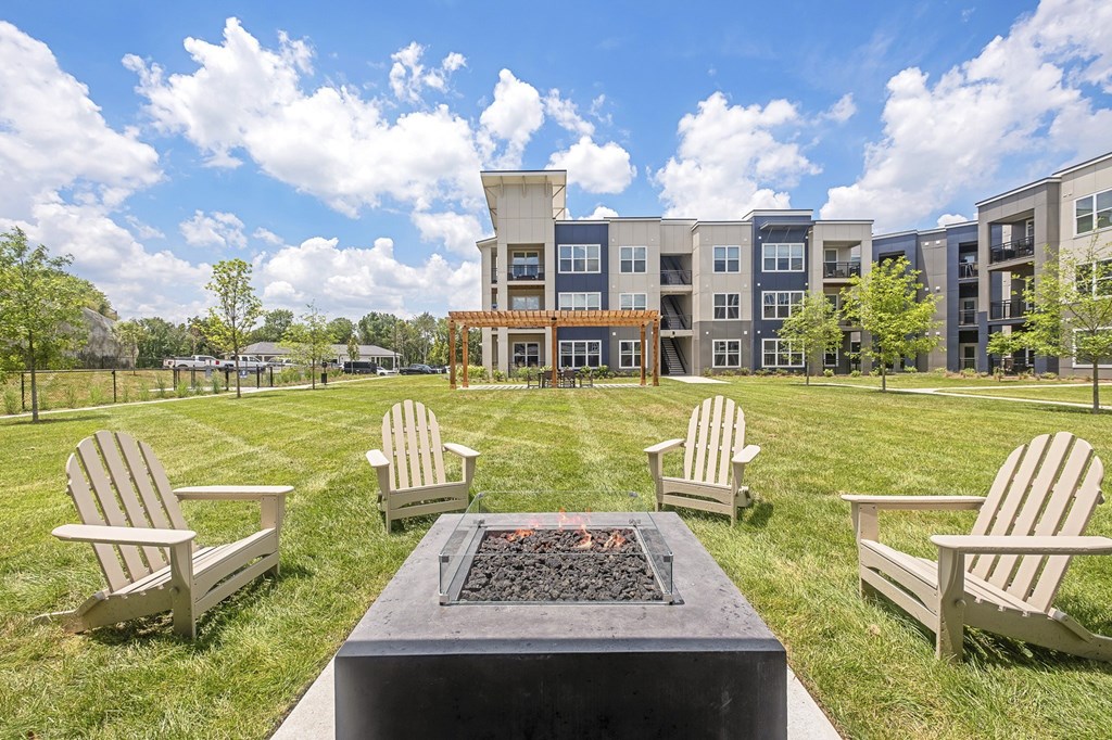 A fire pit sits in the middle of a grassy area with four chairs around it at The Percy Apartments, Tennessee