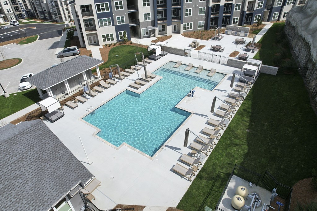 An aerial view of a swimming pool surrounded by lounge chairs and buildings in the background. at The Percy Apartments, Nashville, TN