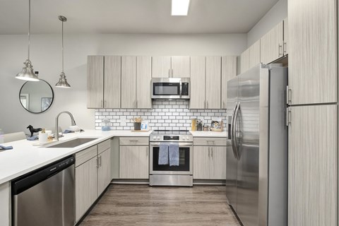 A modern kitchen with a stainless steel refrigerator and wooden flooring.