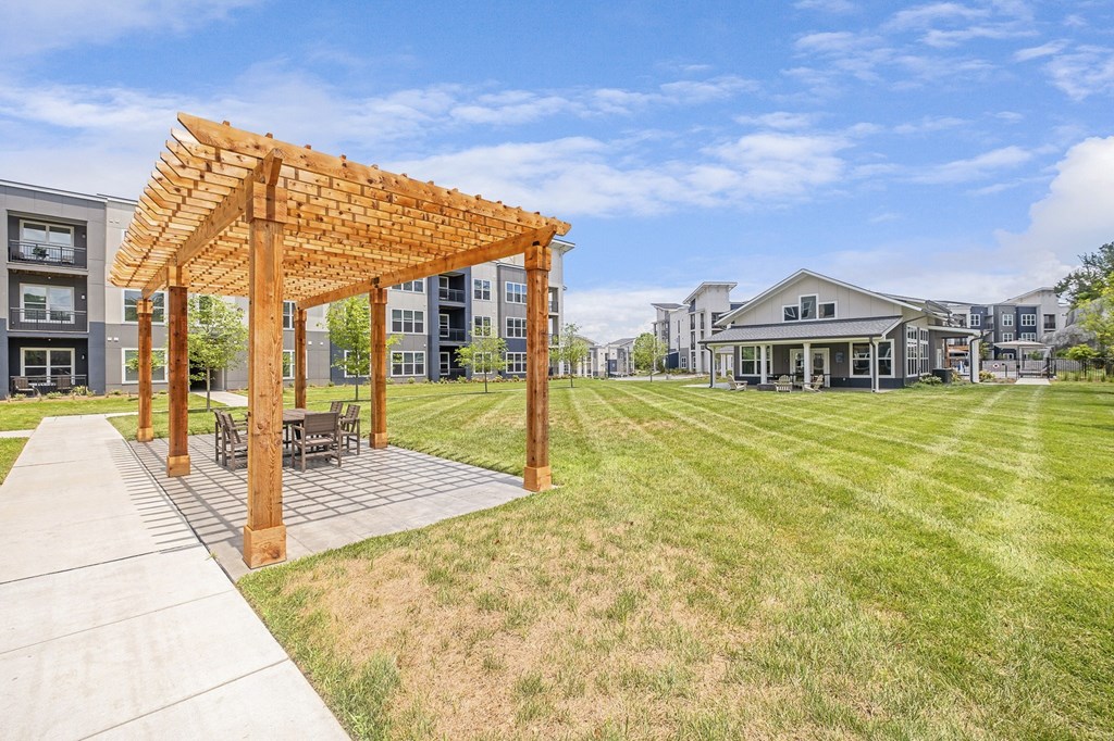 A wooden pergola is situated in a grassy area with a concrete walkway at The Percy Apartments, Tennessee