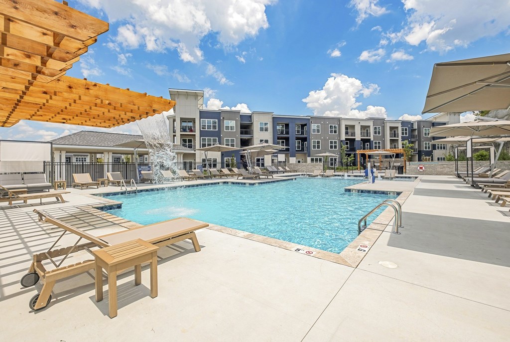 A pool area with a wooden bench and a building in the background at The Percy Apartments, Nashville, TN, 37214