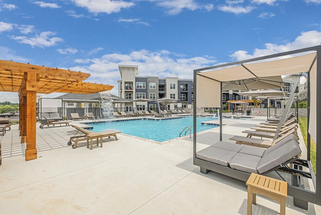 A pool area with sun loungers and a building in the background at The Percy Apartments, Tennessee, 37214