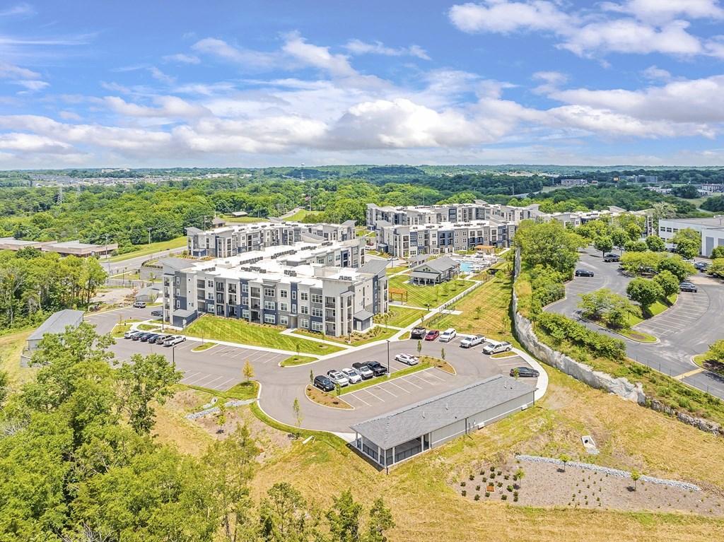 A large, modern building complex with a parking lot in front at The Percy Apartments, Nashville