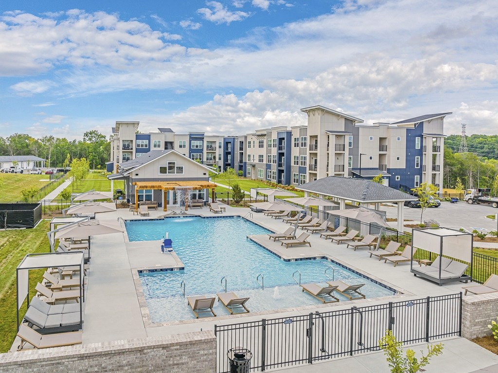 A large swimming pool surrounded by lounge chairs and umbrellas in front of apartment buildings at The Percy Apartments, Tennessee, 37214