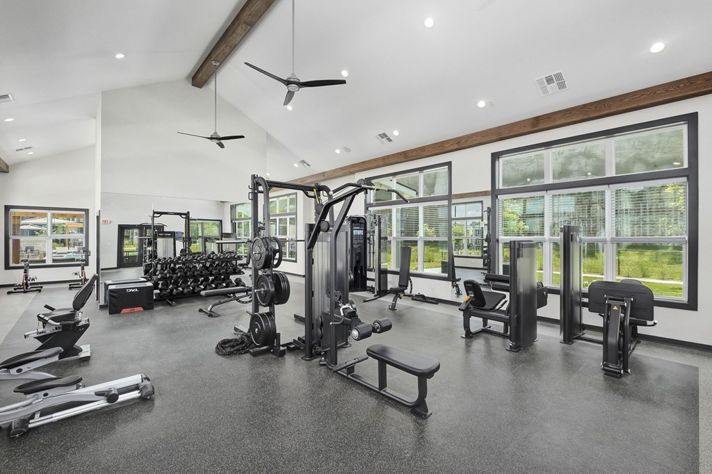 A spacious gym with a variety of equipment including treadmills, weights, and exercise machines at The Percy Apartments, Tennessee