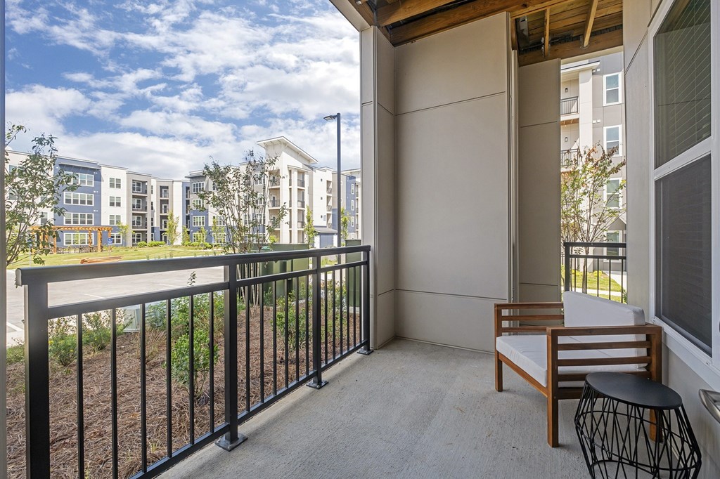 A balcony with a chair and table overlooking a building at The Percy Apartments, Tennessee