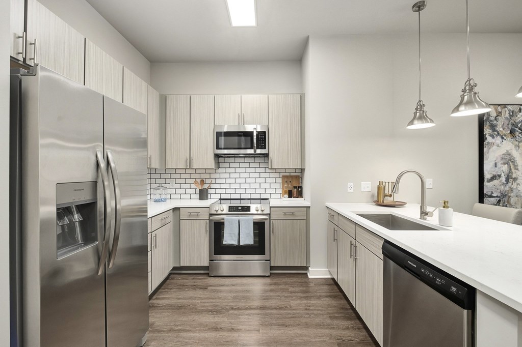 A modern kitchen with a refrigerator, oven, and sink at The Percy Apartments, Tennessee