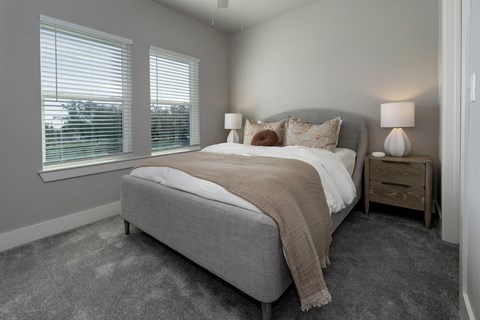 A bedroom with a large bed and two lamps.