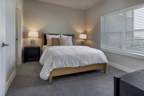 A bedroom with a bed, nightstands, and a window at The Waverly at Winter Haven Apartments, Winter Haven, FL