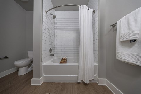 A white bathroom with a toilet, a bathtub, and a towel rack at The Waverly at Winter Haven Apartments, Florida, 33884