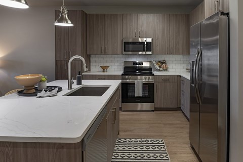 A modern kitchen with a marble countertop and stainless steel appliances at The Waverly at Winter Haven Apartments, Florida, 33884